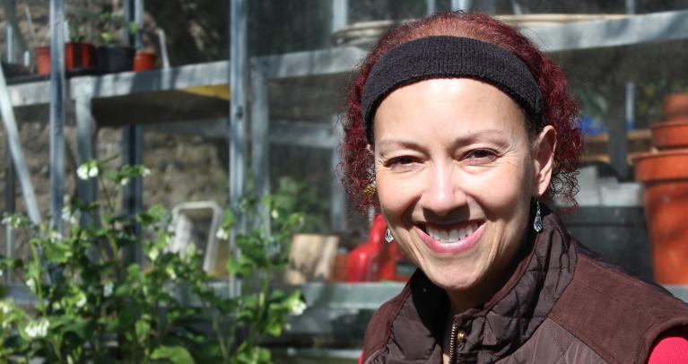 Photo of person smiling with blurred background in greenhouse setting