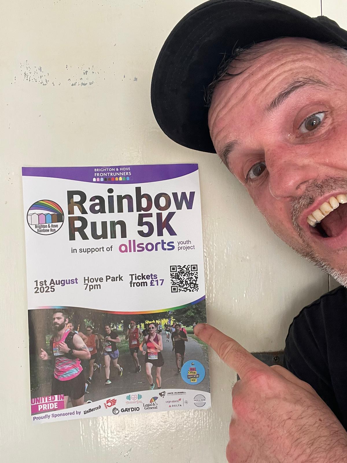 A man named Ben pointing towards poster of Rainbow run, excited. 